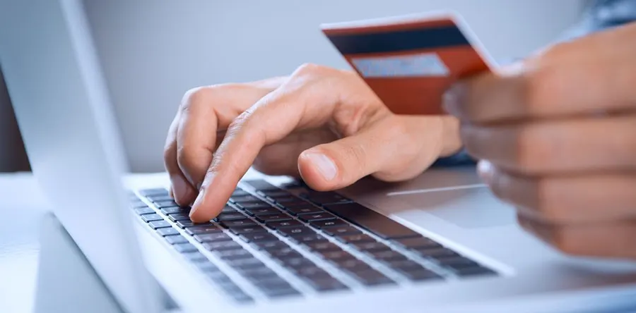 Hands typing on a laptop keyboard while holding a credit card