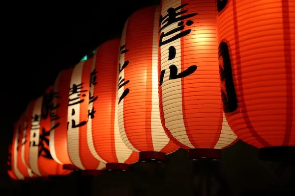 Row of red and white paper lanterns with black lettering, lit at night
