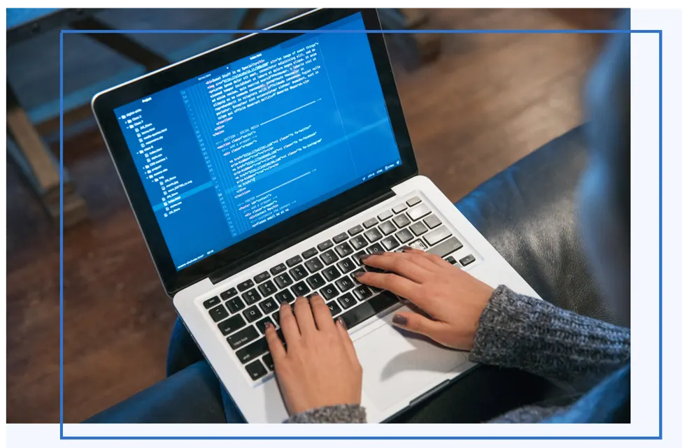 Hands typing HTML code on a laptop