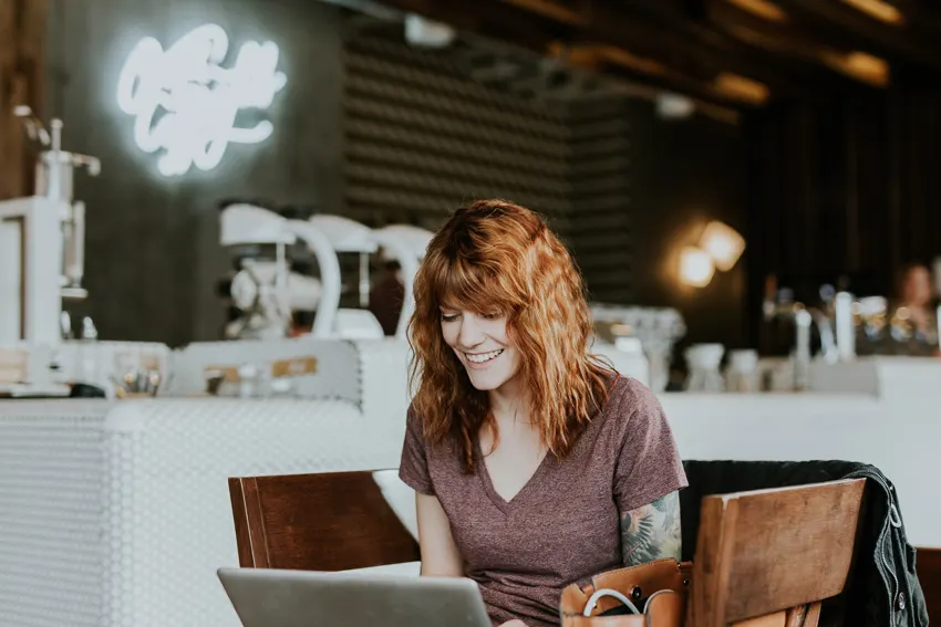 Smiling woman working on a laptop in a café