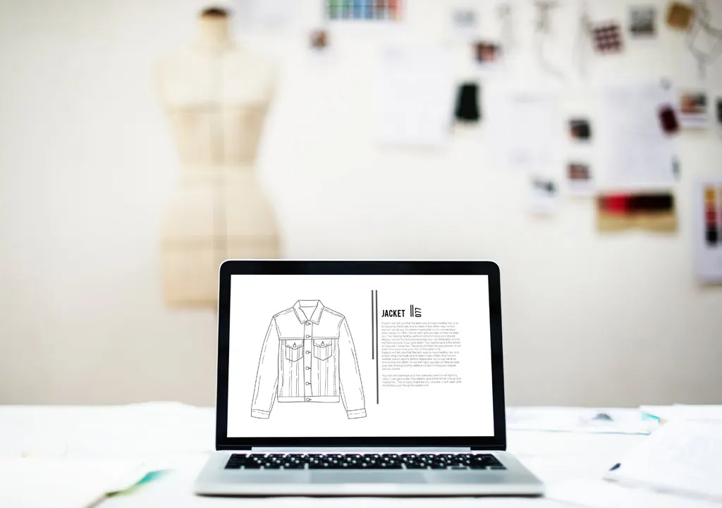 Laptop showing a jacket product sheet in a fashion studio, with a dress form in the background