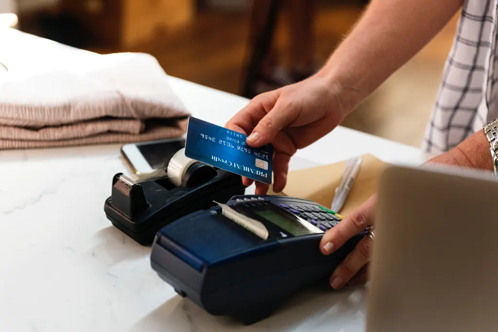 Customer’s card handed over a payment terminal at a shop counter