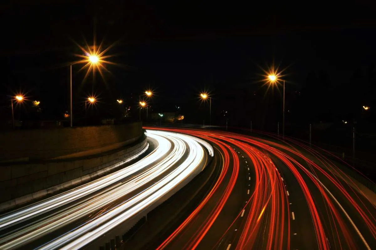 Long-exposure photo of a highway at night with white and red light trails