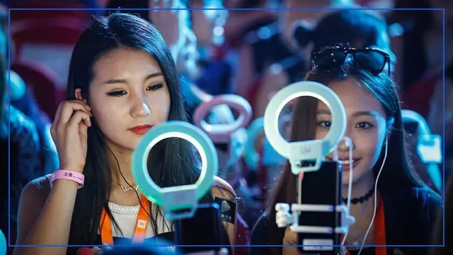 Two live streamers filming themselves with smartphones on ring light stands
