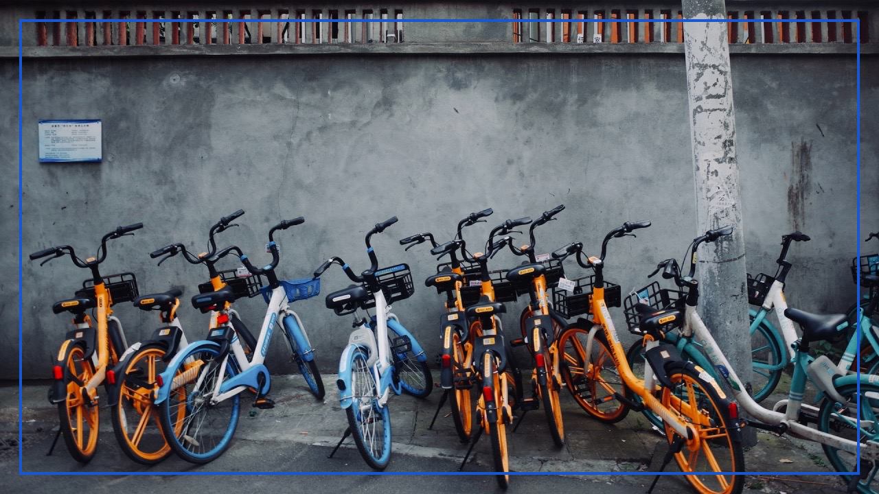 Many sharing bicycles are scatteredly parked on the sidewalk